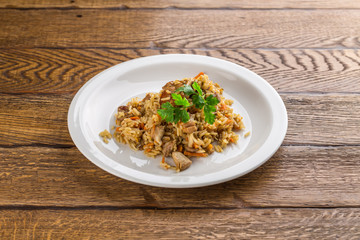 pilaf with lamb on white plate isolated on wooden background