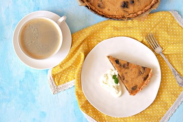 A portion of pumpkin pie with prunes on a white plate on a light blue background. Top view