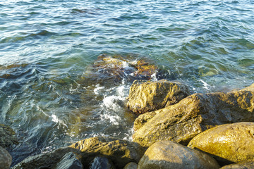 The wreckage of rocks in the sea near the rocky shore in the sea foam.