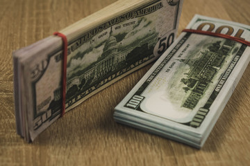 a bundle of american dollars tied with a rubber band on a wooden background.