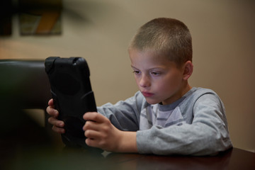 Boy using tablet indoors to learn. 