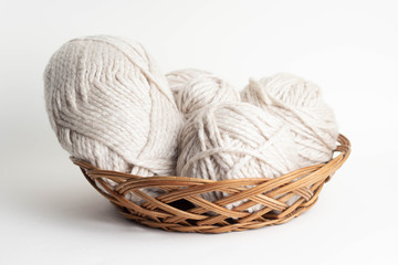 Wool yarn in coils and baals of wool with knitting needles in basket