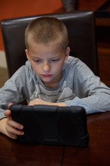 Fototapeta na wymiar Boy using tablet indoors to learn. 