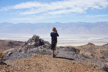 CERRO GORDO, CALIFORNIA/UNITED STATES – SEPTEMBER 3, 2016: Young boy taking photography of the Sierra Nevada mountains from Cerro Gordo, Calfironia.