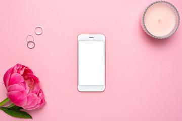 Mobile phone mock up and peony flower on pink pastel table in flat lay style. Woman working desk.Summer colour