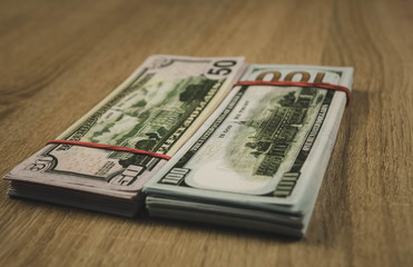 a bundle of american dollars tied with a rubber band on a wooden background.