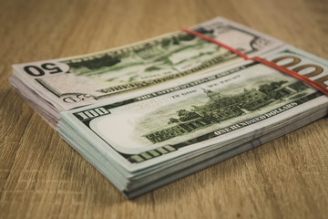 a bundle of american dollars tied with a rubber band on a wooden background.