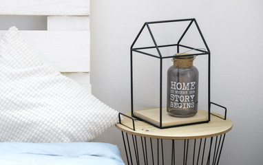 Bottle vase with quote about home inside metal house shape frame on table