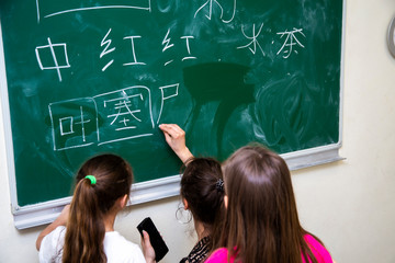 the teacher and children near the school board writes Chinese characters