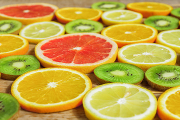 Fototapeta na wymiar slices of oranges, lemons, kiwi, grapefruit pattern on wooden background. Fruit summer background