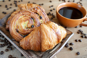 Słodkie śniadanie: czarna kawa, croissant i bułka z rodzynkami