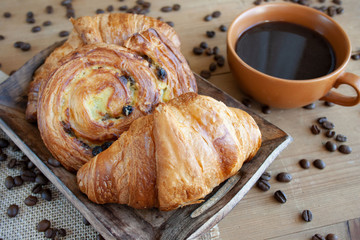 Sweet breakfast: black coffee, croissants and a roll with raisins