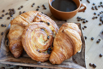 Sweet breakfast: black coffee, croissants and a roll with raisins