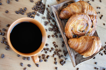 Sweet breakfast: black coffee, croissants and a roll with raisins