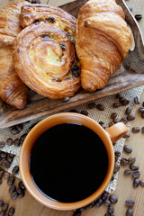 Obraz na płótnie Canvas Sweet breakfast: black coffee, croissants and a roll with raisins