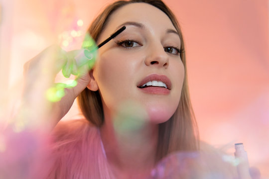 Young woman applying mascara