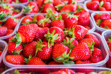 Fresh ripe strawberries in plastic boxes on market