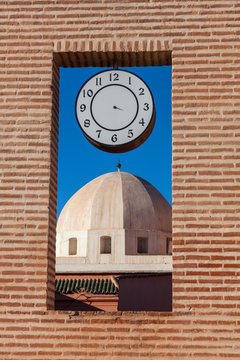 Dome behind brick window with clock in Marrakesh, Morocco