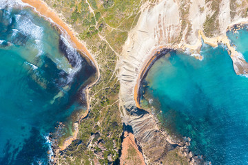 Aerial view from height of the isthmus of the peninsula coastlinescenic sliffs near the mediterranean turquoise water sea. Gnejna and Ghajn Tuffieha bay on Malta island.