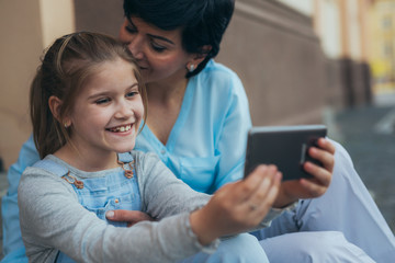 mother and daughter using tablet outdoor in city