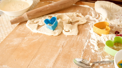 Closeup photo of fresh dough, eggs, milk, and lots of tools for bakery and cooking lying on the big wooden kitchen counterboard