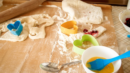 Closeup view from high angle on wooden desk covered with flour, dough, cooking tools and ingredients for cooking and baking at kitchen