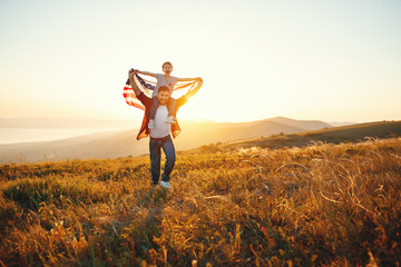 happy family father and child  with flag of united states enjoying  sunset on nature.
