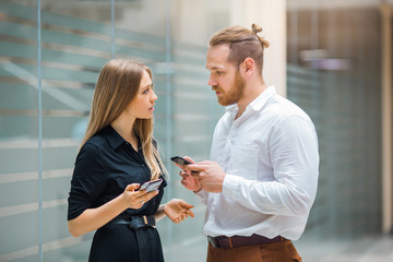 beautiful young man and woman with phones in their hands