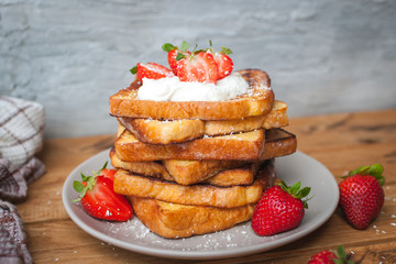 Close-up of french toast with fresh strawberries, coconut shreds and honey, on wooden background