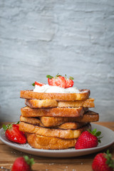 French toast with fresh strawberries, coconut shreds and honey, on wooden background