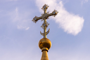 Fototapeta na wymiar Golden dome with a cross against the sky. Orthodox cross in the blue sky. Christianity. Religion. Orthodox Christianity. Jesus. Easter.