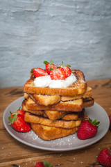 French toast with fresh strawberries, coconut shreds and honey, on wooden background