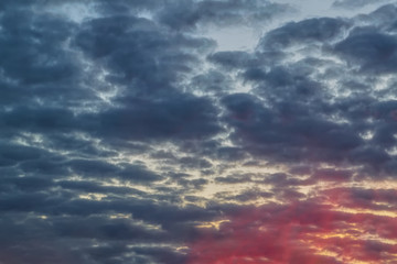 The sky with dark clouds illuminated by the setting sun