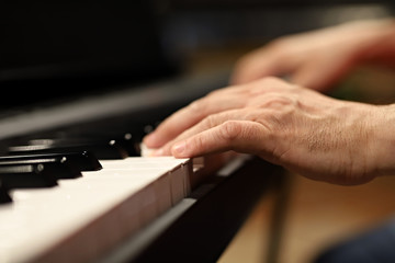Fototapeta na wymiar hands playing piano, one hand, musician playing the piano close-up on the hand, small depth of field on keys