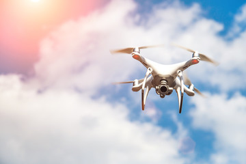 white drone hovering in a bright blue sky. New technology in the aero photo shooting.UAV drone...