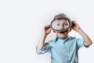 a surprised boy in a blue shirt wearing an underwater mask for swimming on a light background