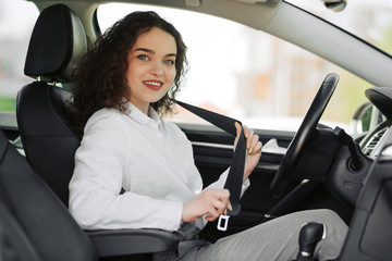 Closeup portrait of young woman fasten seat belt in her car
