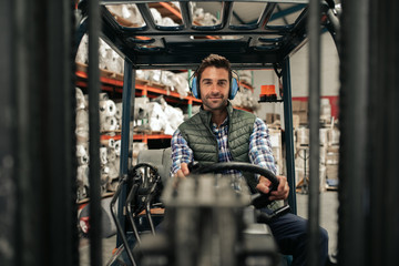 Fototapeta na wymiar Smiling forklift driver working on the floor of a warehouse