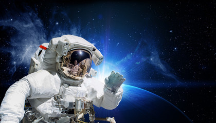 Astronaut in space suit in the space with the sunrise on Earth. Elements of this image furnished by NASA.ce © Eva Kali