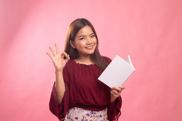 Young Asian woman show OK with a book.