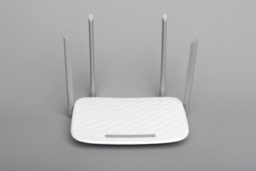 White modern Wi-Fi router with four antennas on a gray background.