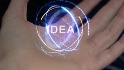 Idea text in a round conceptual hologram on a female hand. Close-up of a hand on a black background with future holographic technology