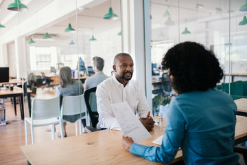 Smiling job applicant answering questions during an office interview - obrazy, fototapety, plakaty