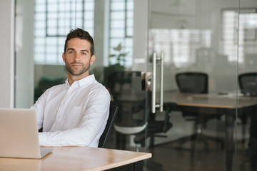 Confident young businessman sitting at his office desk