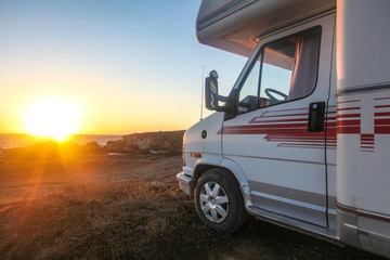 Fototapeta na wymiar Old van or camp truck stands on ocean or sea coast on beautiful sunset of sunrise