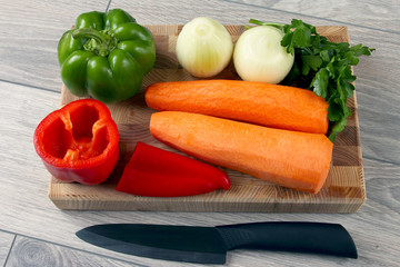 sliced onion and pepper on a kitchen Board with parsley and carrots