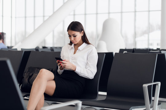 Business woman on her smart phone waiting at the airport