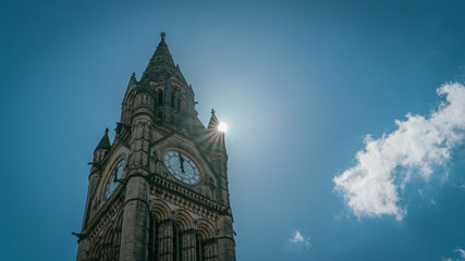 Fototapeta na wymiar Clock tower of tourist place, city hall of Manchester against the sun light. Picture is in vintage tone.
