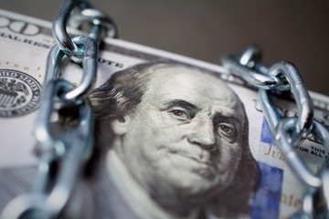 bundle of dollars tied up with a chain, the concept of credit slavery,  frozen assets. dark...