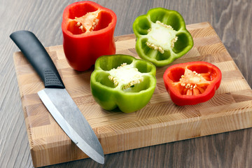 sliced sweet peppers with a ceramic knife on a wooden board